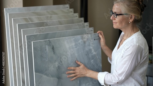 Foto Mature woman with her hand touching a sample of marble stone for flooring and countertops in a design center store for a home renovation redecorating project