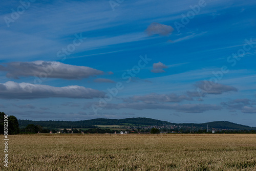 Unter einem Imposant blauem Himmel liegt ein Kornfeld im Vordergrund ,ein OT von Salzgitter in der Mitte und sanfte Hügel des Höhenzug SZ im Hintergrund photo