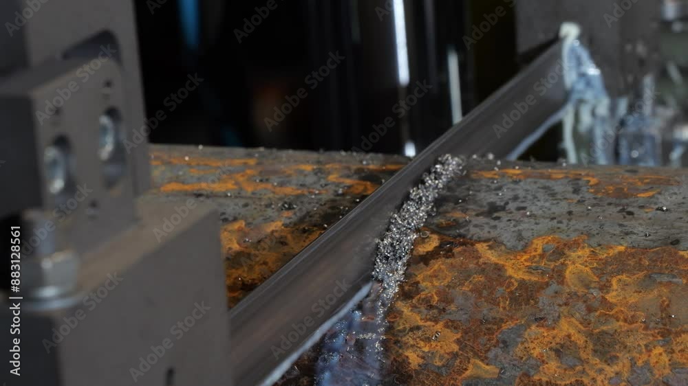A black and orange metal surface with a piece of metal being cut with a saw A black and orange metal surface with a piece of metal being cut with a saw