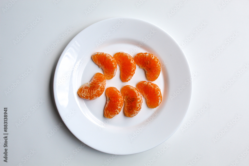 Some orange fruit segments, on white plate, isolated on white background, flat lay or top view Some orange fruit segments, on white plate, isolated on white background, flat lay or top view