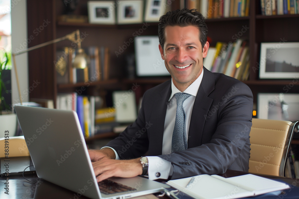 financial director or banker working on a laptop at his office desk, exuding confidence and success as he smiles at the camera. Ideal for business and finance themes. Photo