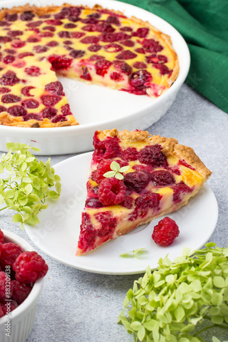 A piece of raspberry pie on a plate and hydrangea flowers. Seasonal summer baking..