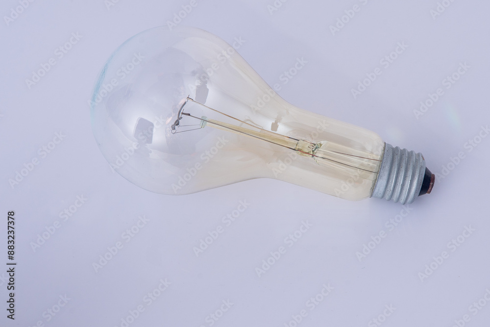 An old glass light bulb with a tungsten filamen on white background. Metal base. Retro technology An old glass light bulb with a tungsten filamen on white background. Metal base. Retro technology