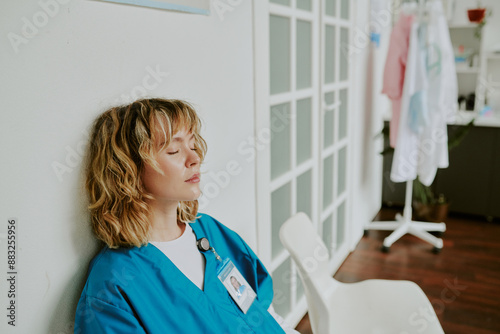 High angle shot of young Caucasian nurse sitting with her eyes closed after night shift while she sitting in on call room