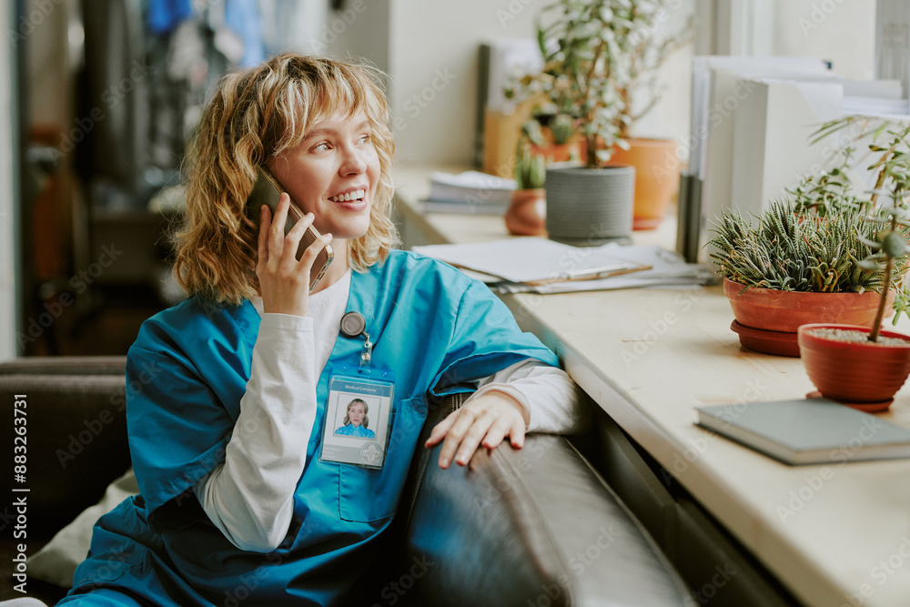 Young Caucasian doctor looking out window while enjoying conversation in on call room