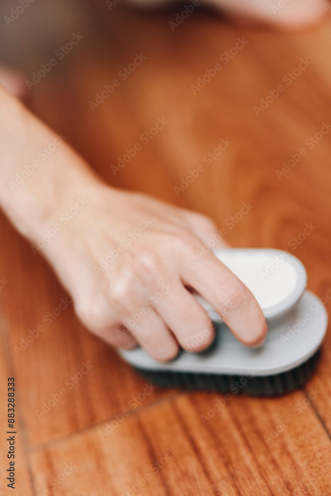 Fototapeta premium Person cleaning wooden floor with a brush, white object on top