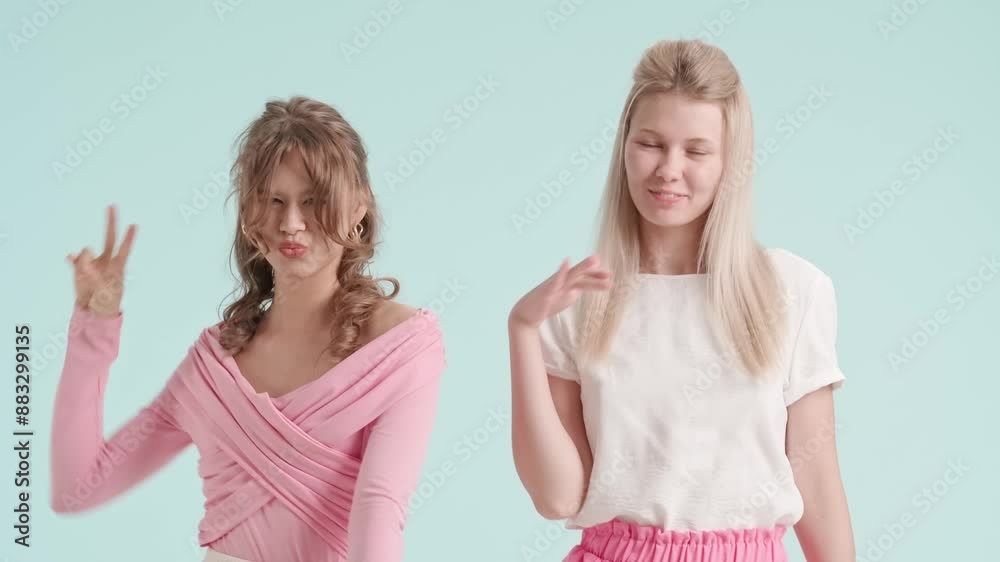 Young fashionable women models playfully funny dancing and smiling, isolated on blue background. Fashion and youth beauty concept. Young fashionable women models playfully funny dancing and smiling, isolated on blue background. Fashion and youth beauty concept.