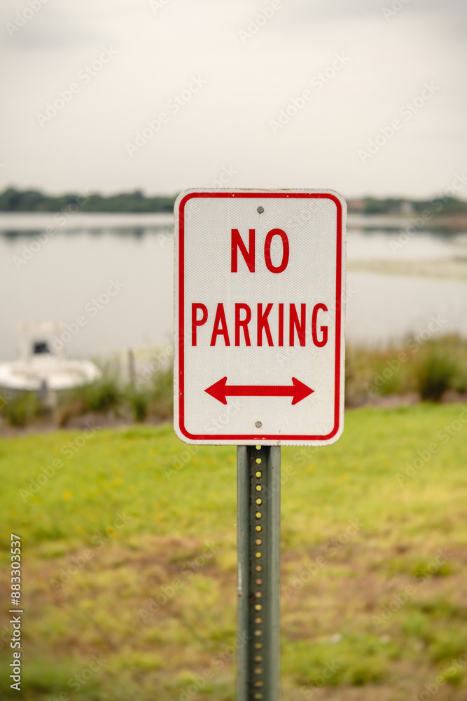 no parking sign by a lake, close-up with a boat in the background, vertical no parking sign by a lake, close-up with a boat in the background, vertical