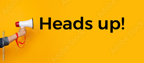 Person with a megaphone and a text saying heads up