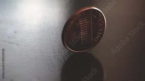 Copper penny spinning on a wooden tabletop in slow motion; 240fps 4k footage
