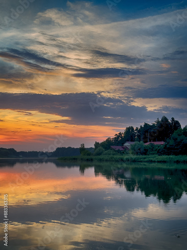 Serene Fishing Lake: A peaceful scene by the tranquil waters of a secluded fishing lake. Surrounded by lush greenery and framed by a clear blue sky, this picture captures the essence of a perfect day 