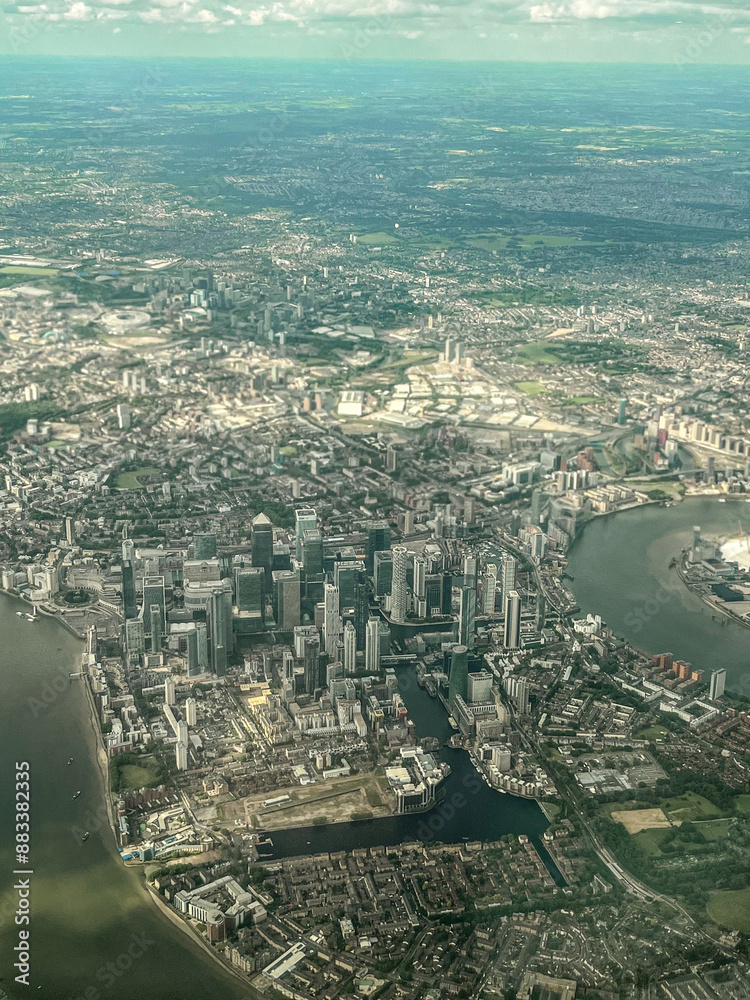 Fototapeta premium Aerial view of London. View of the city centre of London from the window of the plane. Flying over the city with blue and grey landscapes. View of the river and skyscrapers.