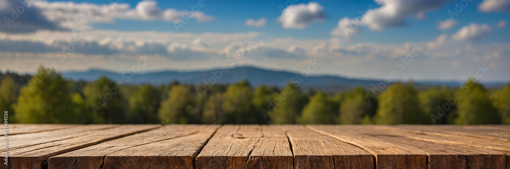 Close-up shot of empty, wooden surface with blurred background showing forest and mountain range under blue sky Close-up shot of empty, wooden surface with blurred background showing forest and mountain range under blue sky