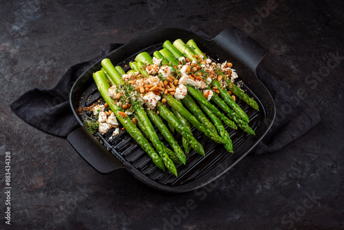 Obraz na plátně Green asparagus glazed with Greek feta cheese, roasted pine nuts and cress on se