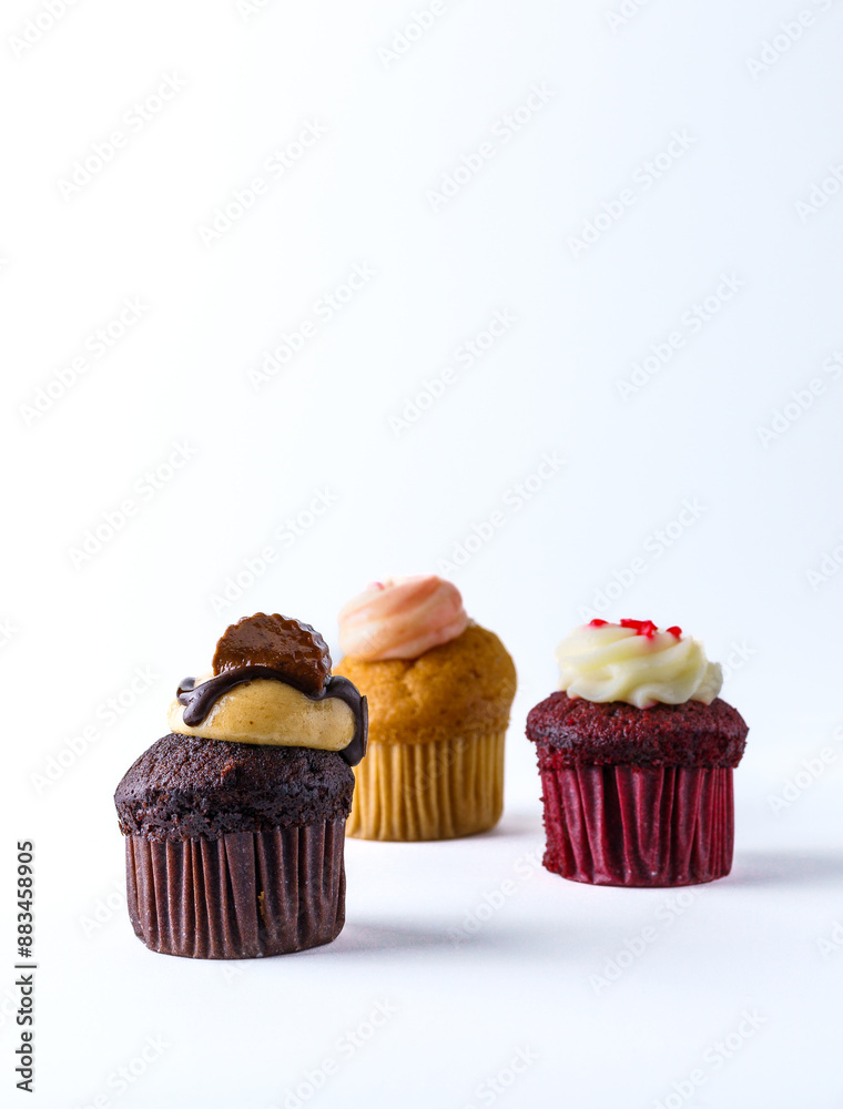 Neat, small cupcakes decorated with sweets and cream on a white background. Neat, small cupcakes decorated with sweets and cream on a white background.