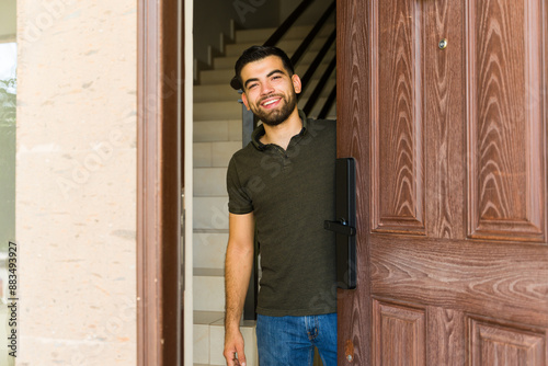 Obraz na plátne Man greets guests with a warm smile at his front door, creating a welcoming atmo