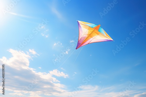 Multi colored kite flying high in the blue sky