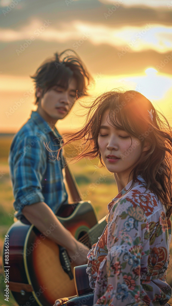 Japanese woman singing with an extremely handsome Japanese man playing guitar, open field with gently blowing wind and setting sun. Japanese woman singing with an extremely handsome Japanese man playing guitar, open field with gently blowing wind and setting sun.