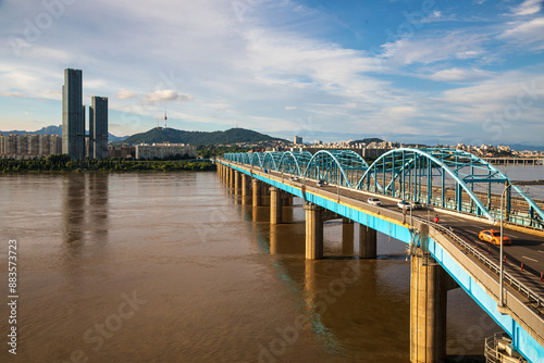 Dongjak-gu, Seoul, South Korea - July 18, 2023: Summer view of flood and muddy water of Han River with Dongjak Bridge against apartments and Gangbyeon Expressway
 photo