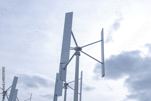 Vertical axis wind turbines stand tall against a cloudy sky, representing renewable energy and the advancement of sustainable technology in the fight against climate change. photo