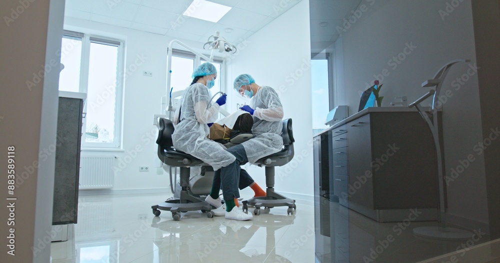 Dentist and Assistant Treating Patient in Clinic Dentist and Assistant Treating Patient in Clinic