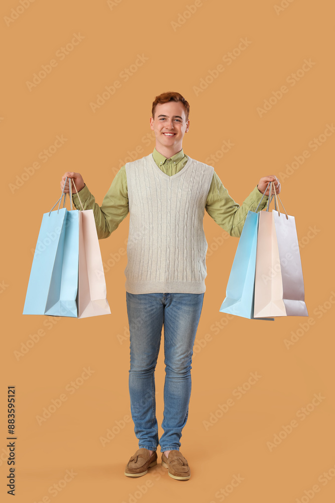 Young man with shopping bags on beige background Young man with shopping bags on beige background