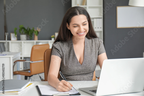 Pretty businesswoman writin...
