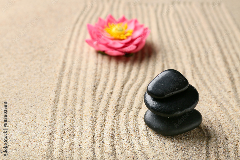 Fototapeta premium Black spa stones and flower on light sand with lines. Zen concept