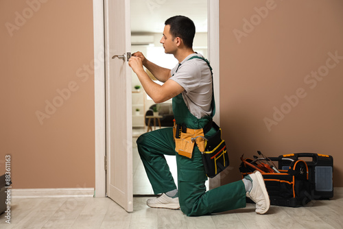 Photography Male worker with screwdriver repairing door at home