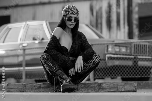 Fashion street. Sexy fashion woman sitting outdoor. Dangerous areas. Fashionable brunette in black jacket bandana and sunglasses in urban style. Lifestyle of female hipster. Casual dress style.