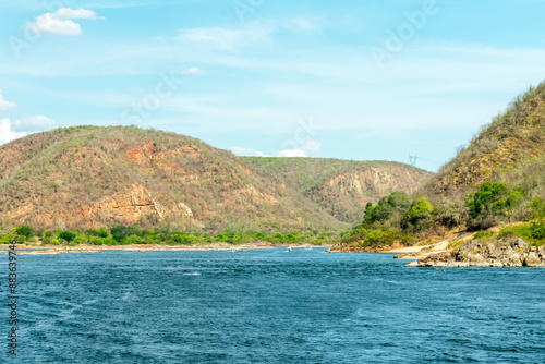 Image of the riverbed with mountains in the background and blue sky with clouds. of the São Francisco River in Piranhas, state of Alagoas, northeast of Brazil.