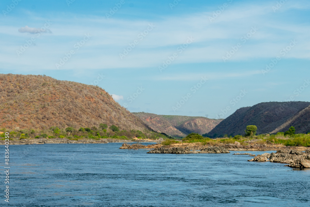 Image of the riverbed with mountains in the background and blue sky with clouds. of the São Francisco River in Piranhas, state of Alagoas, northeast of Brazil. Image of the riverbed with mountains in the background and blue sky with clouds. of the São Francisco River in Piranhas, state of Alagoas, northeast of Brazil.