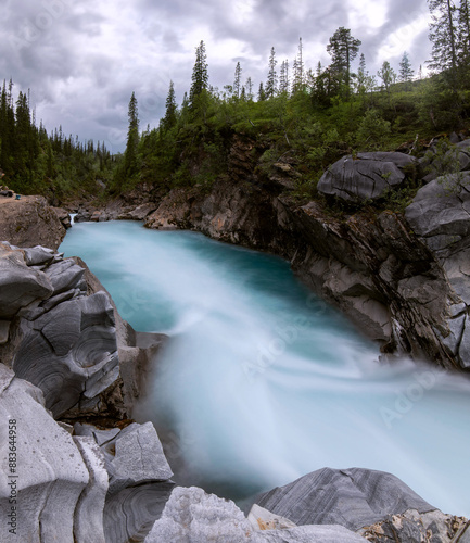 Long exposure of flowing river Marmorslottet in Rana, Helgeland, Norway. Wild stream through marble rocks turned to softness in 10 second exposure. Smooth marble rock formations with turquoise rapids photo