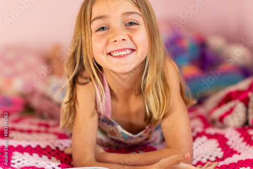 young blonde girl resting on her bed with crocheted blanket