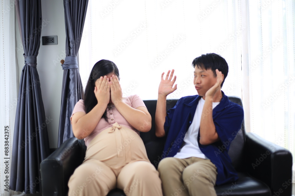 Obraz premium An asian couple seems very happy. A handsome husband is embracing his beautiful pregnant wife next to the window in the living room.Pregnant woman with husband holding ultrasound baby image.