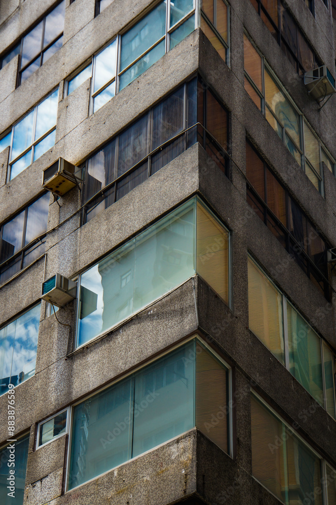 A gray concrete building with numerous windows, air conditioners, and balconies A gray concrete building with numerous windows, air conditioners, and balconies