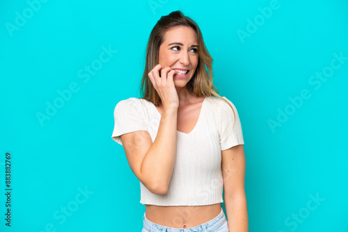 Young caucasian woman isolated on blue background is a little bit nervous photo