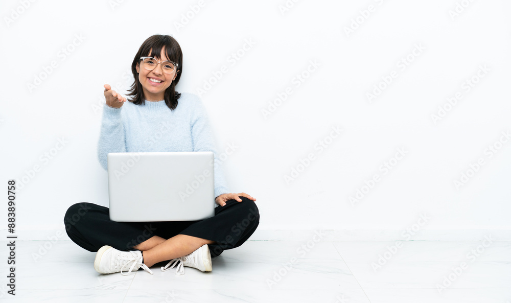 Young mixed race woman sitting on the floor with laptop isolated on white background shaking hands for closing a good deal Young mixed race woman sitting on the floor with laptop isolated on white background shaking hands for closing a good deal