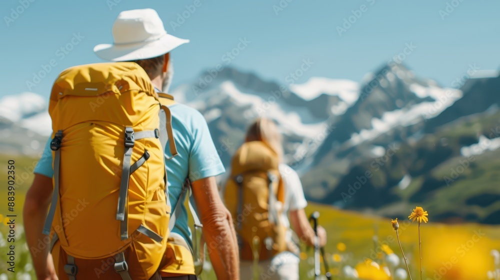 Fototapeta premium A group of adventurers hike through a scenic mountain landscape, their journey taking them through vibrant, blooming meadows with snowy peaks in the distance.