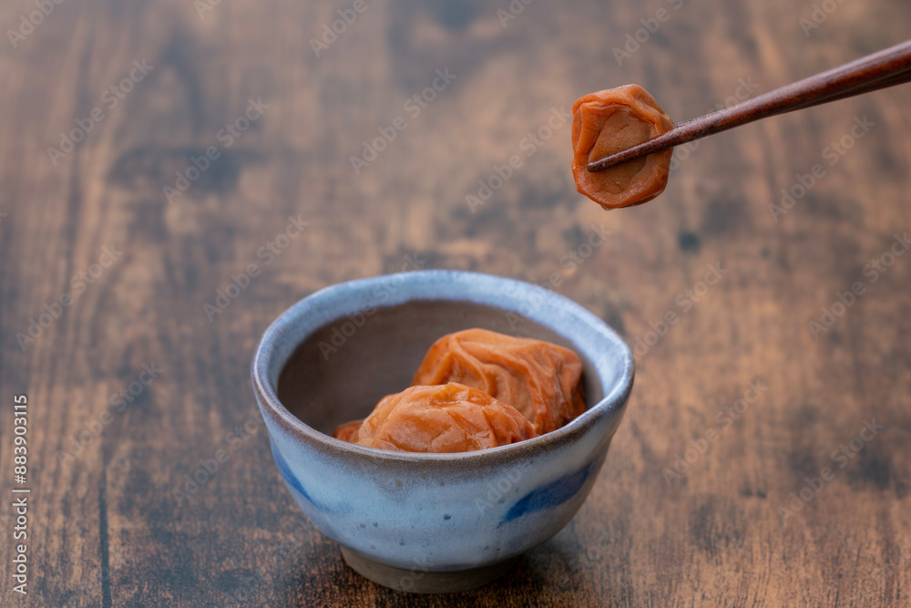 小皿に入った梅干しと箸でつまんだ梅干し 小皿に入った梅干しと箸でつまんだ梅干し