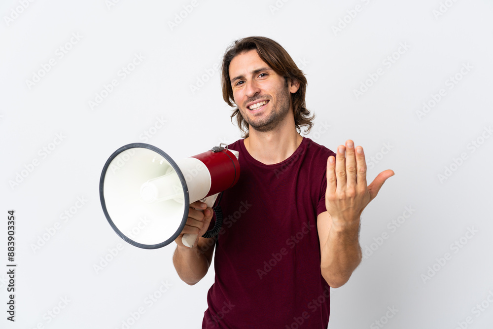 Young handsome man isolated on white background holding a megaphone and inviting to come with hand Young handsome man isolated on white background holding a megaphone and inviting to come with hand