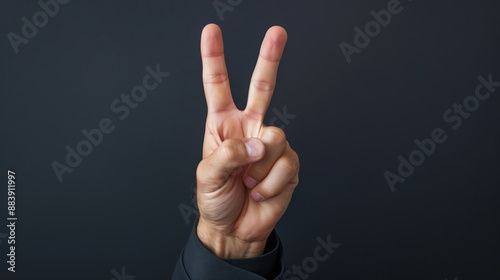 Business hand showing a peace sign against dark background, negotiation success photo