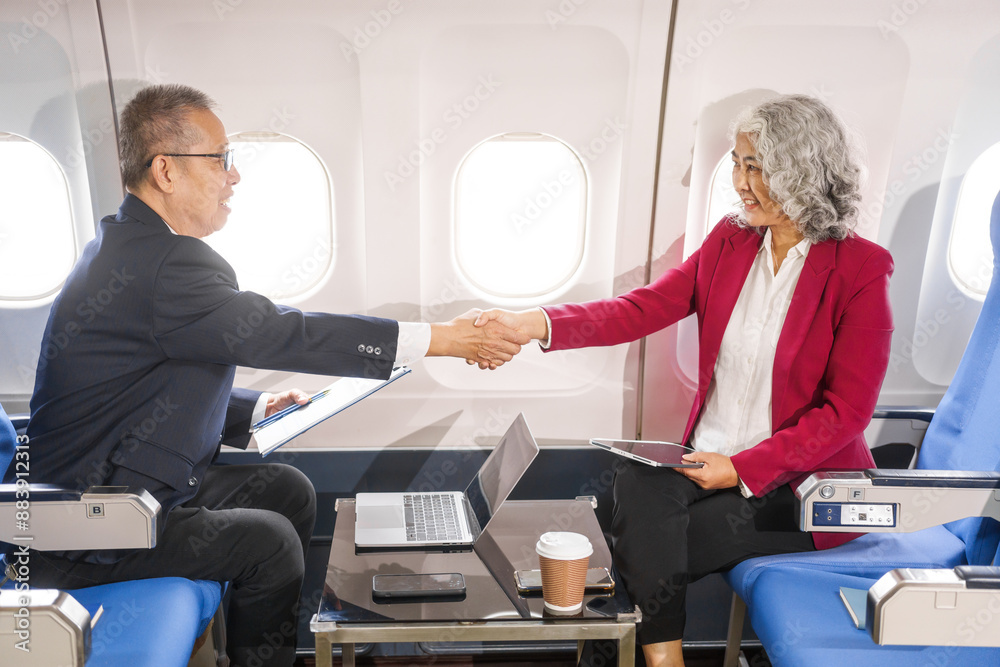 Fototapeta premium A businessman, an adult man, and a woman are meeting and talking aboard an airplane. They hold hands, symbolizing camaraderie or support during their professional discussion.