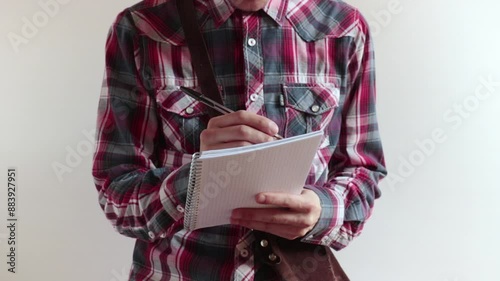person takes notes, he writing on a block of paper sheets extracted from a vintage shoulder bag
