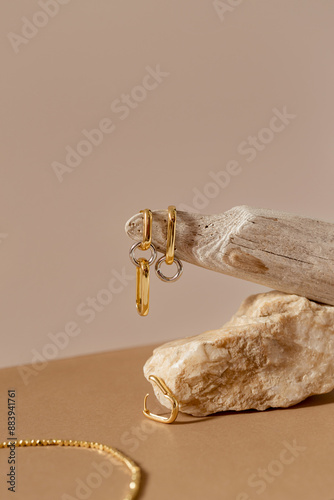Golden earrings and necklace on pastel beige background. Stylish jewellery set
