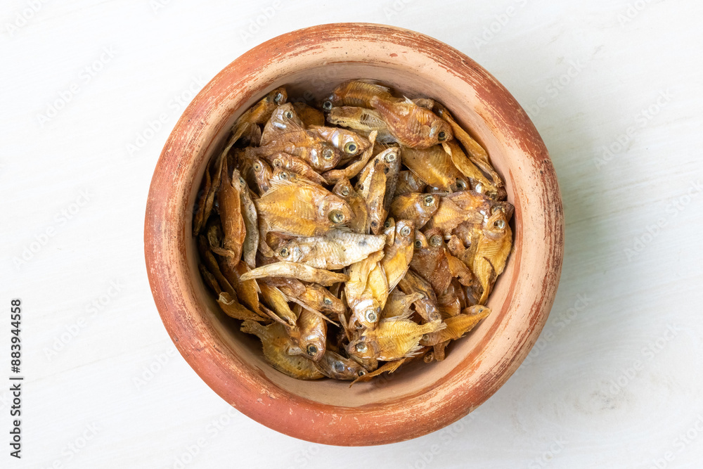 Dried rupchanda shutki or chinese pomfret fish in earthen pot on light white wooden background. Top view. Dried rupchanda shutki or chinese pomfret fish in earthen pot on light white wooden background. Top view.