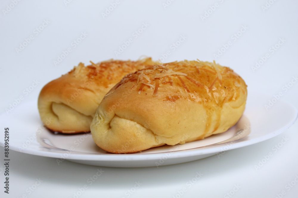 Two baked bread with grated cheese on top, on white plate, isolated on white background Two baked bread with grated cheese on top, on white plate, isolated on white background