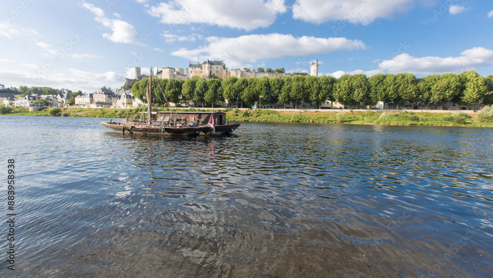 Obraz premium toue, traditional boat on the Vienne at the foot of the fortified town of Chinon in Indre-et-Loire in France in summer