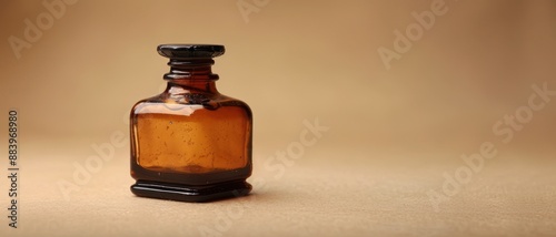 An amber glass bottle with a black lid sits on a light brown surface.