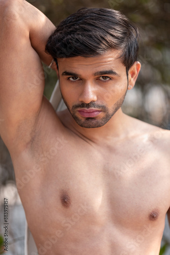 Close-up portrait of a confident, handsome, athletic Indian man, shirtless, revealing his sensual body, showcasing his rich facial expressions, exuding a calm and peaceful demeanor